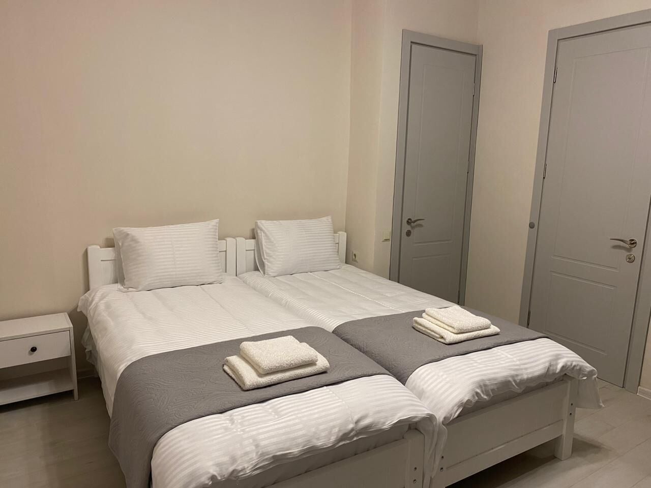 Quarto com uma cama, duas mesas de cabeceira e duas portas.