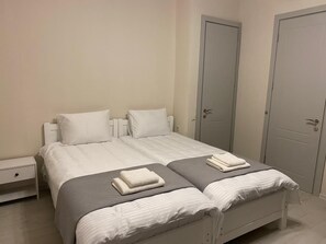 Quarto com uma cama, duas mesas de cabeceira e duas portas.