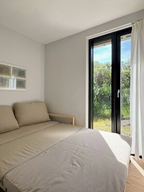 A bedroom with a bed, a window, and a view of greenery outside. - Terrace with a sea peek, 500 meters from the beach (ordrup)