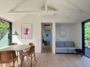 A modern interior with a dining area, a sofa, and a view through a large window. - Terrace with a sea peek, 500 meters from the beach (ordrup)