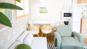 A compact living space with a kitchenette, a dining area with chairs, a sofa, and a green armchair. - MSTAY Kamata Honcho (Ota-ku)