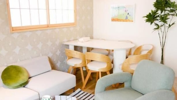 A compact living space with a sofa, a dining table with chairs, a glass coffee table, and a striped rug. - MSTAY Kamata Honcho (Ota-ku)