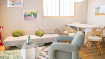 A living room with a sofa, chairs, a glass coffee table, and artwork on the walls.