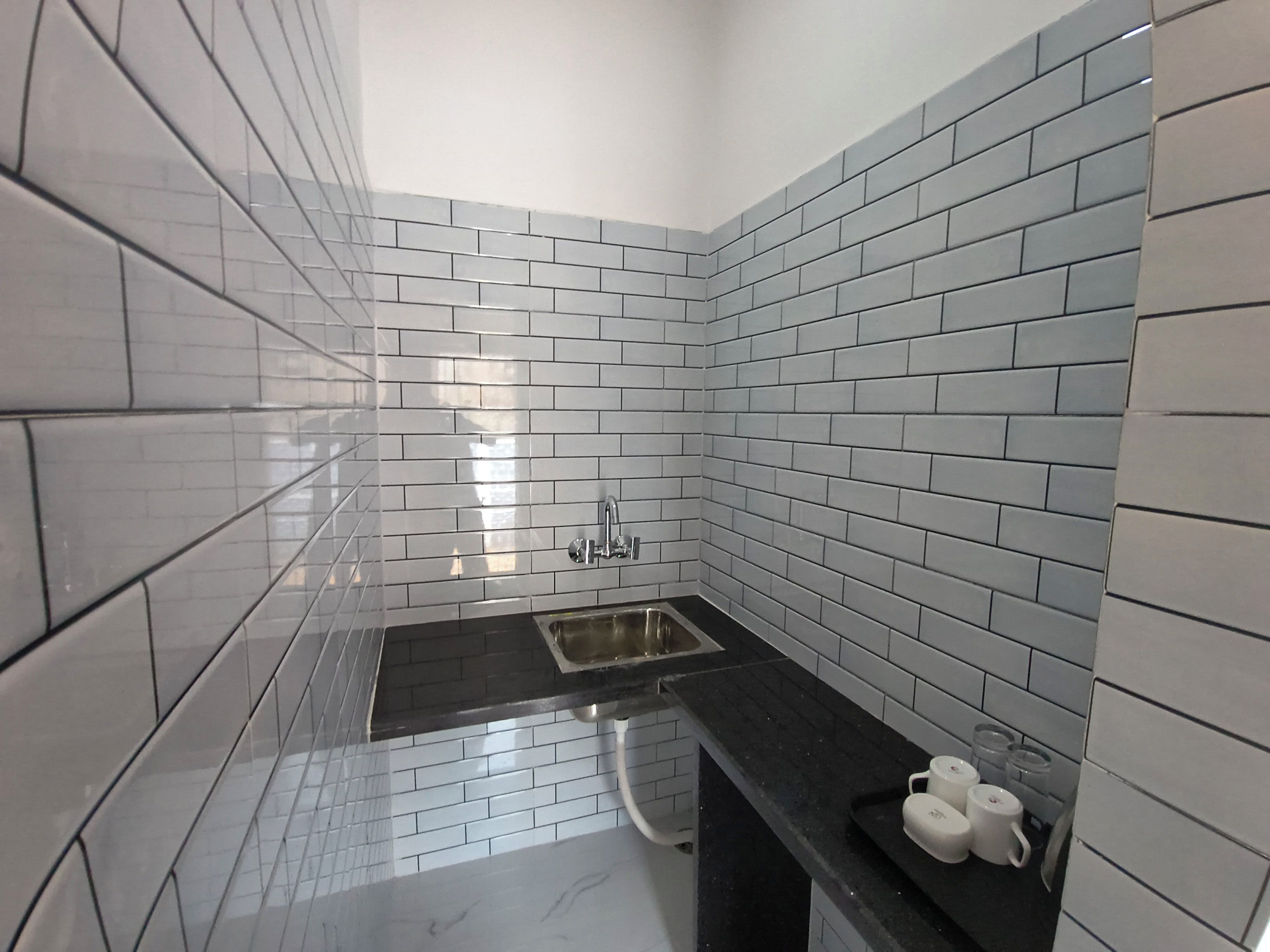 A bathroom with white subway tiles, a black countertop, and a stainless steel sink.