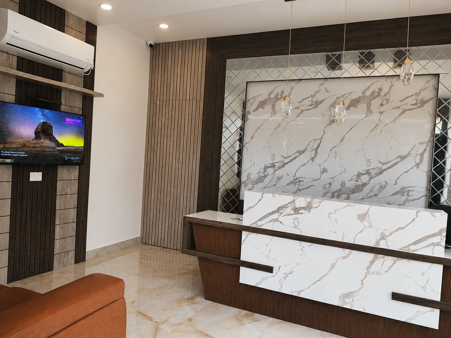 Un baño moderno con tocador de mármol, televisor montado y pared revestida de madera.