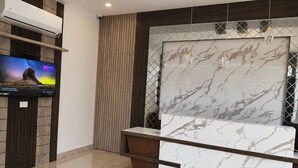A modern bathroom with a marble vanity, a mounted TV, and a wooden panel wall. - Asusss International (Kanthi)