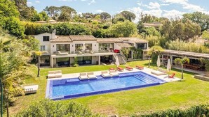 Una casa moderna con piscina, zona de estar exterior y jardín.