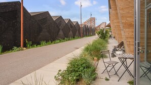 A sidewalk with a row of black geometric structures, a wooden building with a glass door, and a clear sky. - Beautiful apartment in Aarhus C with WiFi (Aarhus C)