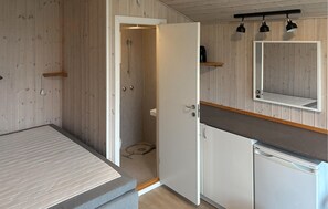 A compact room with a bed, a shower, a sink, and a mirror. - Cozy home in Samsø with house sea view (Samsø)