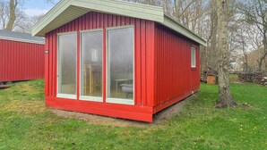 Eine rote Holzhütte mit großen Fenstern und einem geneigten Dach.