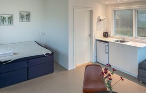 Une petite chambre comprenant un lit, une kitchenette et une fenêtre.