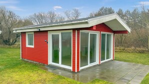 Un bâtiment rouge à un seul étage, doté d’un porche couvert et de grandes portes vitrées.