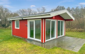 A red single-story building with a covered porch and large glass doors. - Beach front home in Samsø with house sea view (Samsø)