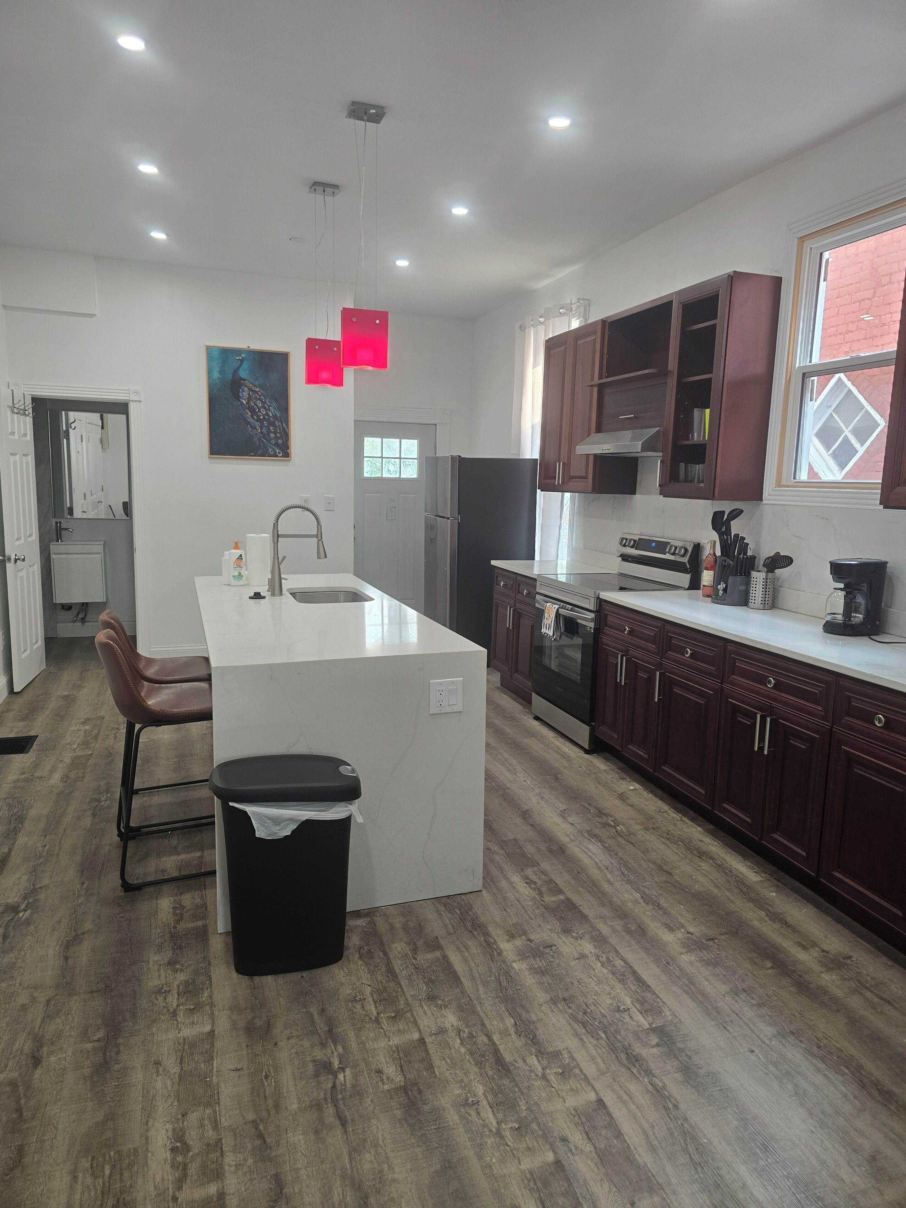 A modern kitchen with a central island, wooden cabinets, a refrigerator, and a window with a view.
