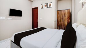 A hotel room with a bed, a television mounted on the wall, and a door leading to another room. - Collection O Sector 33 Gurgaon (Gurugram)