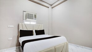 A bedroom with a bed, a wall-mounted air conditioner, and a power outlet. - Collection O Sector 33 Gurgaon (Gurugram)