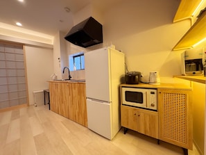 A compact kitchen with a refrigerator, microwave, and a coffee maker on the counter. - Teradamachi (Tennoji Ward)