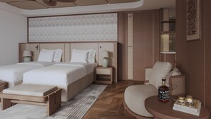 Une chambre d’hôtel avec deux lits, un coin salon, une petite table avec une bouteille et un ventilateur de plafond.