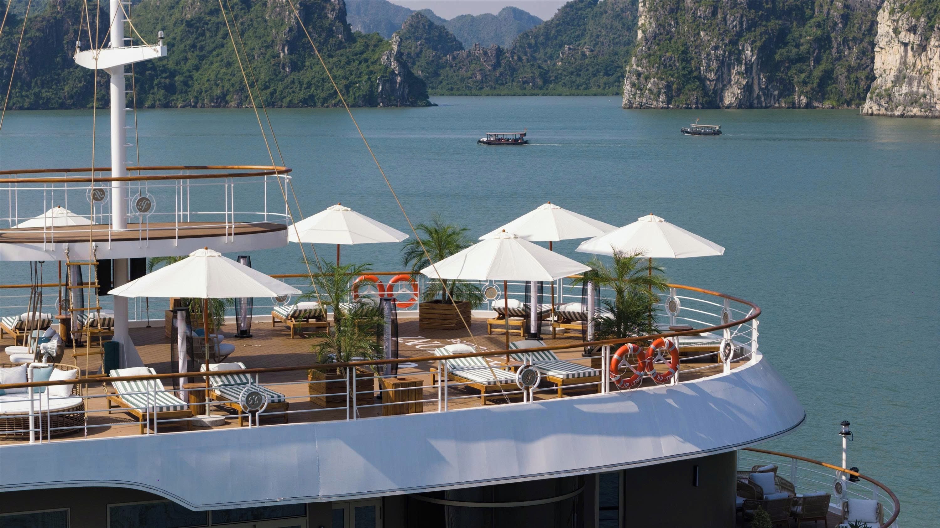 A cruise ship deck with sun loungers, umbrellas, and lifebuoys.