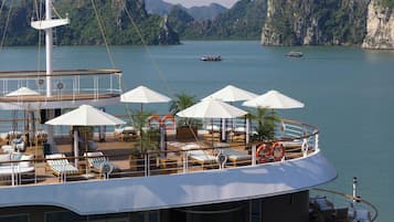 A cruise ship deck with sun loungers, umbrellas, and lifebuoys.