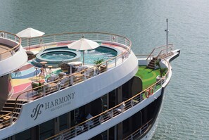 A cruise ship with a swimming pool, lounge area, and outdoor seating. - Harmony Boutique Cruise (Tuan Chau)