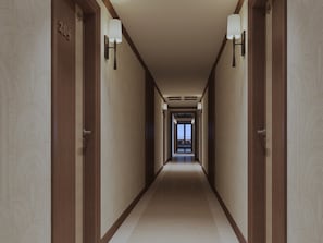A hotel hallway with wooden doors, numbered room signs, and wall-mounted lamps. - Harmony Boutique Cruise (Tuan Chau)