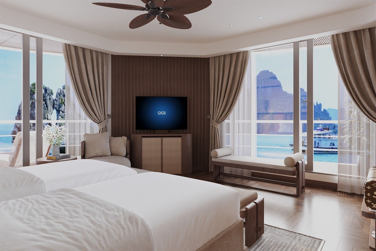 A modern hotel room with a large bed, a flat-screen TV, and a balcony with a view of the sea.