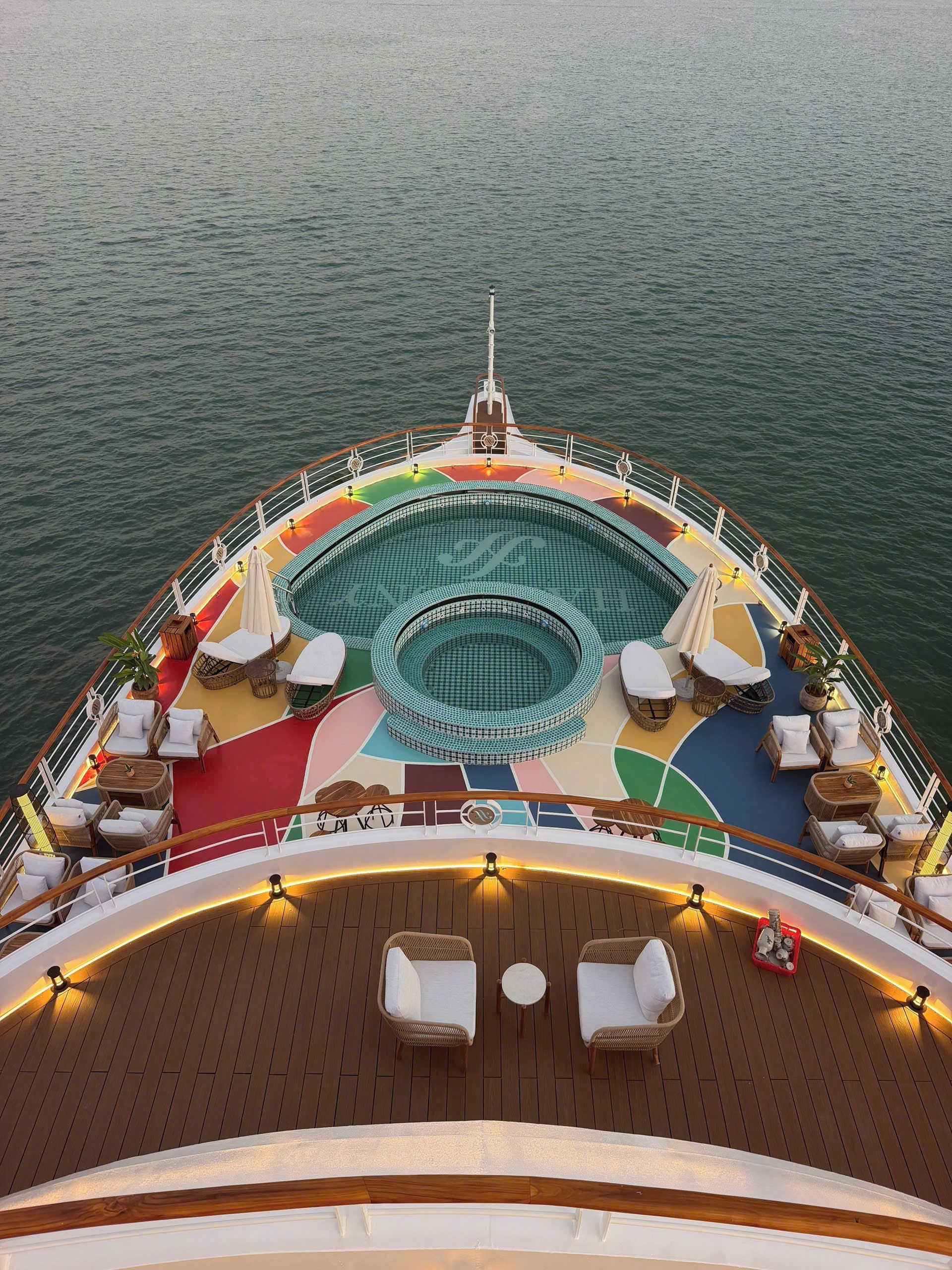 A deck with a pool, lounge chairs, and a wooden floor.