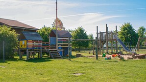 Ein Spielplatz mit Holzkonstruktionen, darunter eine Rutsche und Klettergerüste.