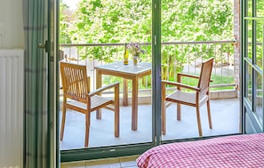 A balcony with two wooden chairs and a table, a checkered tablecloth, and a view of greenery through a glass door. - Awesome apartment in Ribnitz-Damgarten with WiFi (Ribnitz-Damgarten)