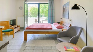 A hotel room with a bed, a desk with a television, a chair, a table, and a window with curtains. - Awesome apartment in Ribnitz-Damgarten with WiFi (Ribnitz-Damgarten)