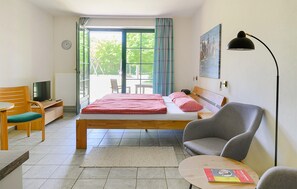 A hotel room with a bed, a desk with a television, a chair, a table, and a window with curtains. - Awesome apartment in Ribnitz-Damgarten with WiFi (Ribnitz-Damgarten)