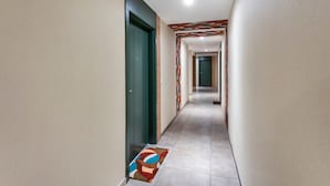 Un corridoio con tappeto decorato, una porta verde e un pavimento piastrellato.