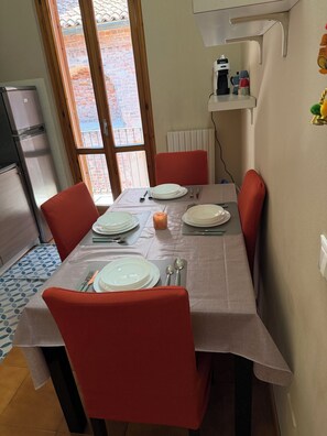 A dining area with a table set for four, equipped with plates, cutlery, and a candle. - Dragonfly Pavia (Pavia)