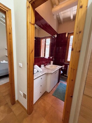 A bathroom with a wooden door, a sink, and a mirror. - Dragonfly Pavia (Pavia)