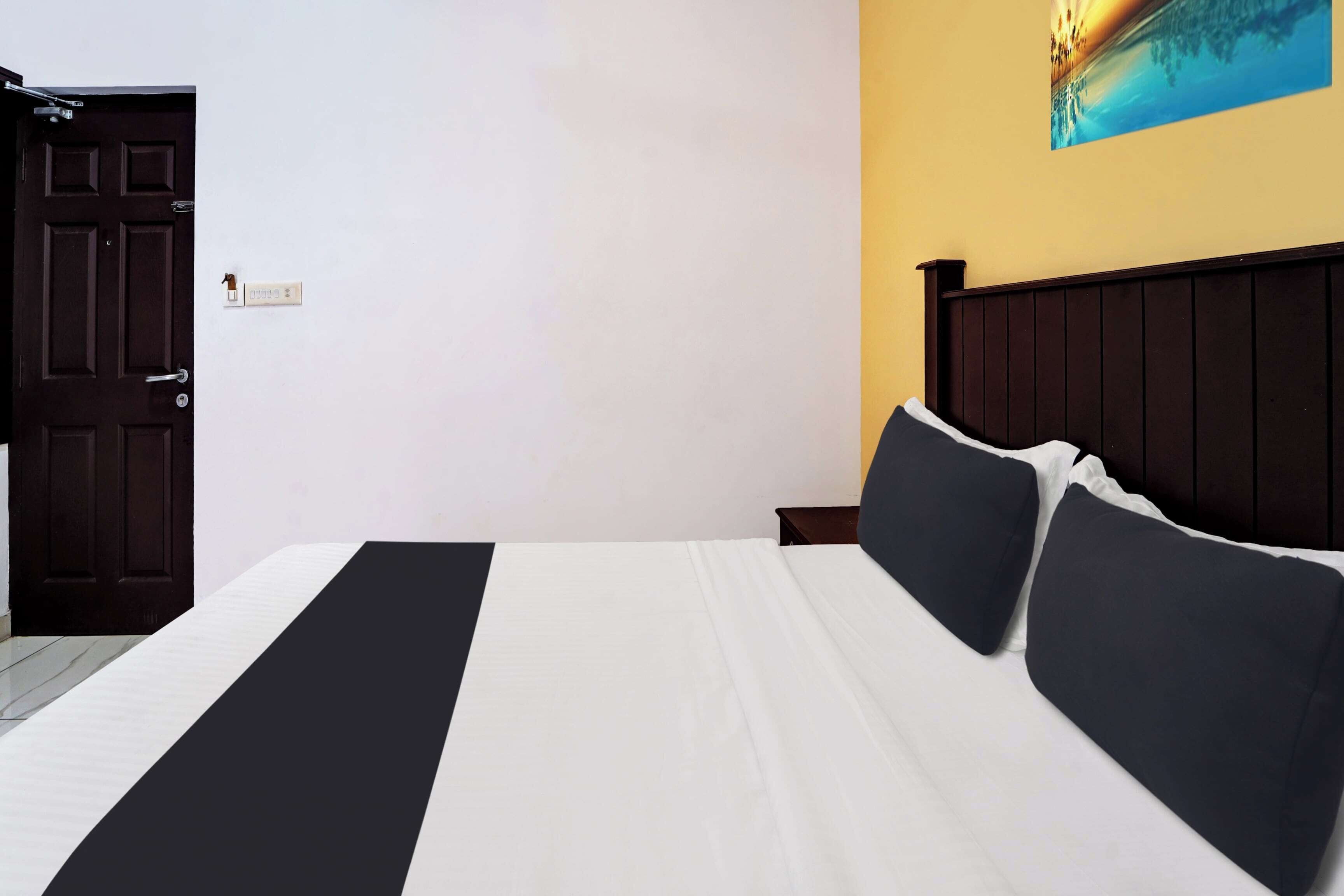 Une chambre à coucher avec un lit, une table de chevet, une porte et un interrupteur fixé au mur.