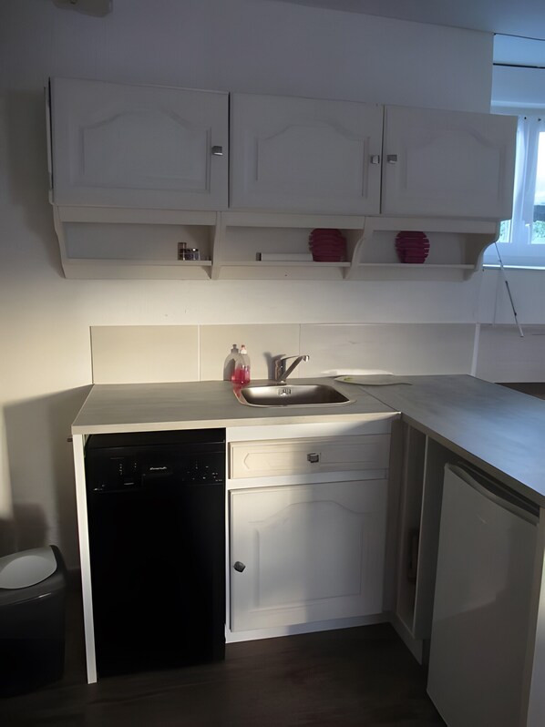 A compact kitchen with white cabinetry, a dishwasher, and a sink.