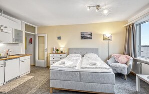 A hotel room with a bed, bedside table, chair, and a view of the outdoors. - Stunning apartment in Schleswig with WiFi (Schleswig)