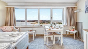 A room with a dining table set for four, a sofa, and a view of a landscape through large windows. - Stunning apartment in Schleswig with WiFi (Schleswig)