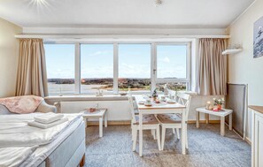 A room with a dining table set for four, a sofa, and a view of a landscape through large windows. - Stunning apartment in Schleswig with WiFi (Schleswig)