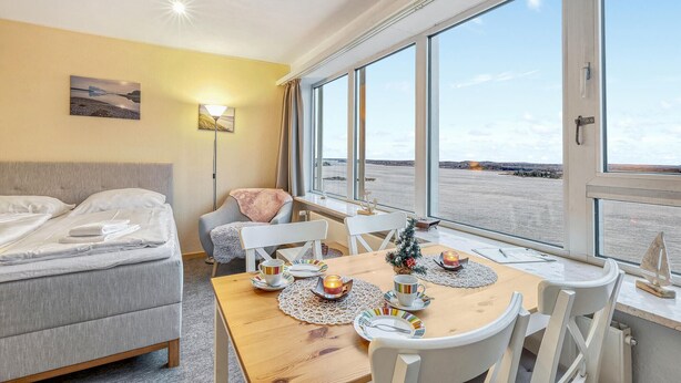 A hotel room with a bed, a table set for two with a candle, and a view of a river. - Stunning apartment in Schleswig with WiFi (Schleswig)