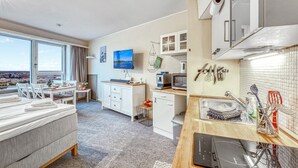 A modern hotel room with a large window, a dining area, a kitchen with appliances, and a view of the city. - Stunning apartment in Schleswig with WiFi (Schleswig)