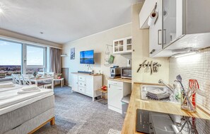 A modern hotel room with a large window, a dining area, a kitchen with appliances, and a view of the city. - Stunning apartment in Schleswig with WiFi (Schleswig)