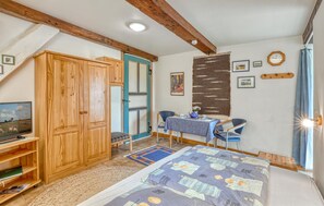 Een slaapkamer met een bed, een bureau, een stoel, een kledingkast en een televisie.