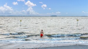 A beach with waves, a person in red shorts, and two yellow markers in the water. - Nice apartment in Niebüll with WiFi (Niebüll)