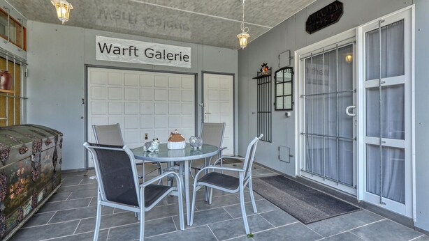 Un comedor con una mesa y sillas, una maleta antigua y un letrero que dice "Warft Galerie".