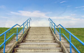 A set of concrete stairs with blue handrails leading up a grassy hill under a clear sky. - Stunning apartment in Galmsbüll with WiFi (Galmsbüll)