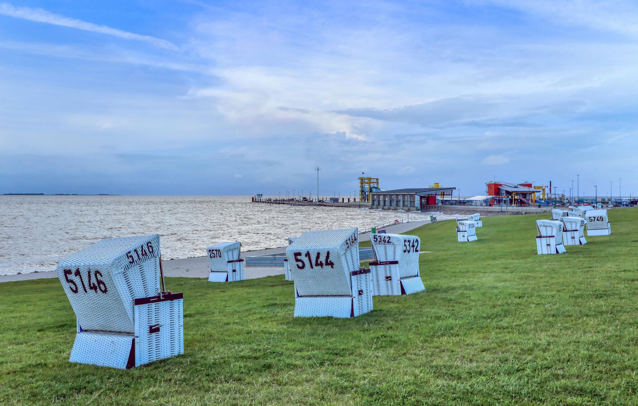 Zona de playa con sillones de baño numerados y un edificio al fondo.
