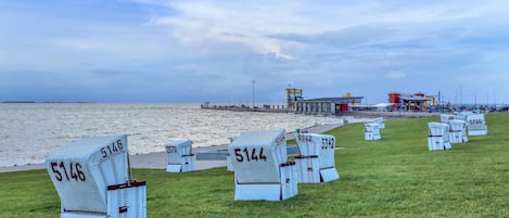 Une zone de plage avec des chaises longues numérotées et un bâtiment en arrière-plan.