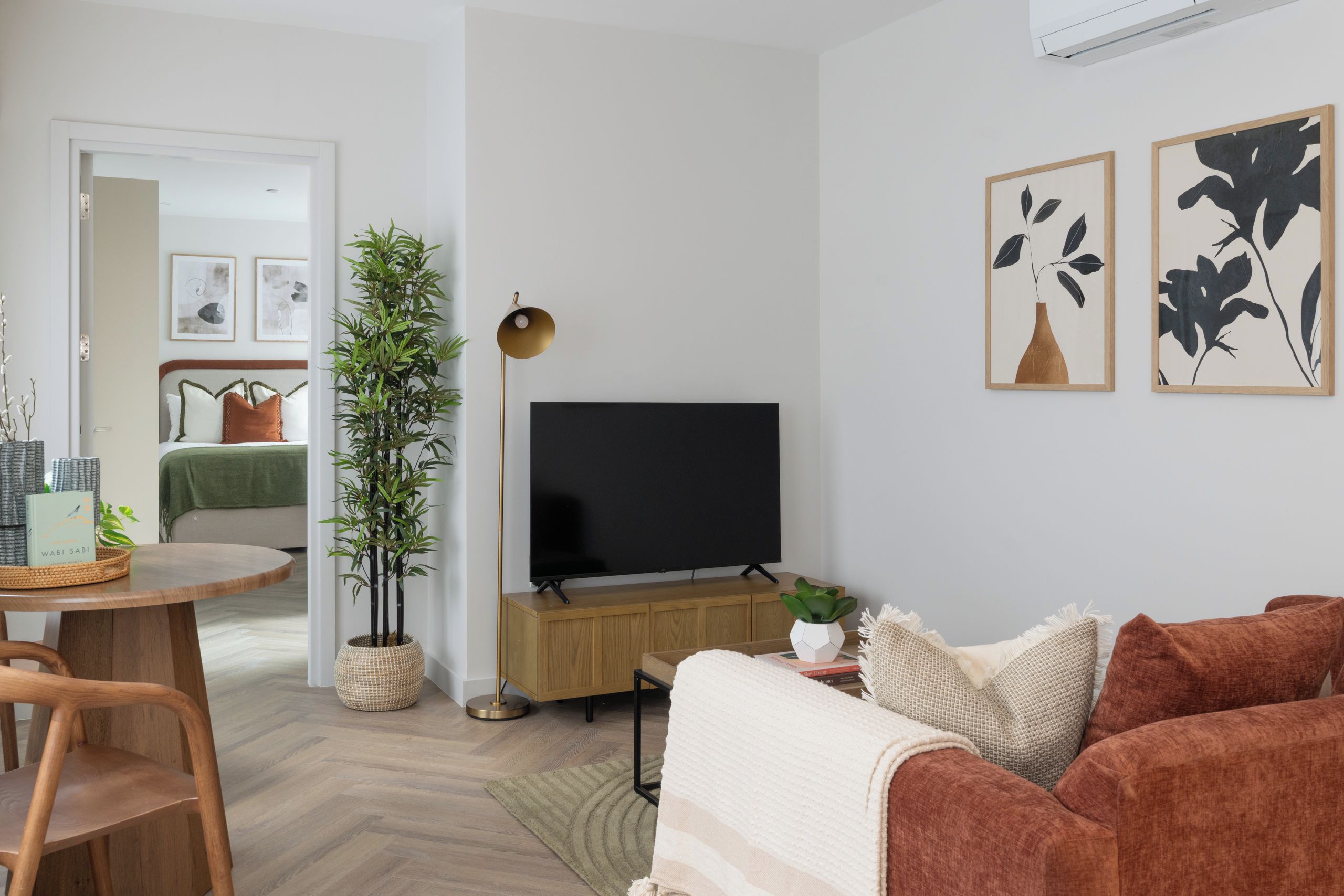 A living room with a TV, sofa, and a dining area with a table and chairs.